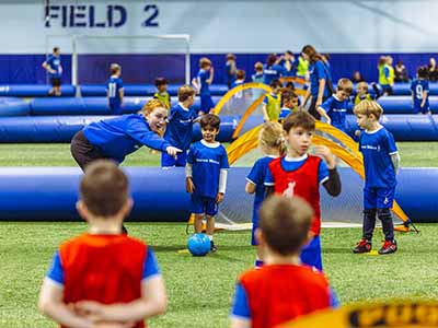 Kids playing soccer in different classes on a big indoor field