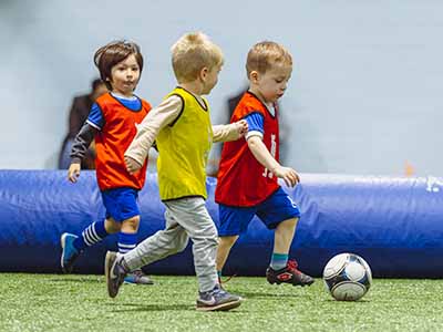 Kids running on a turf field playing a soccer scrimmage