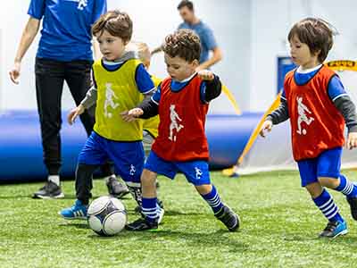 Kids wearing pinnies playing soccer scrimmage