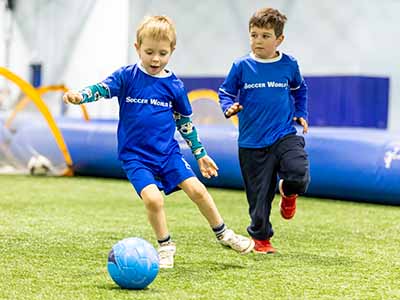 2 kids chasing a soccer ball